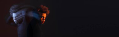 Yaralı ve bunalımlı, siyah arka planda bipolar bozukluğu olan, turuncu ve mavi ışıklı Afro-Amerikan bir adam.