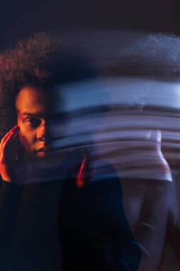 double exposure of abused african american man with bipolar disorder touching injured bleeding face on dark background with orange and blue light clipart
