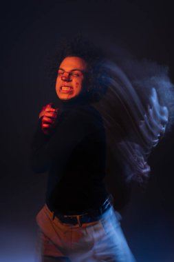 İki kez suistimal edilmiş, bipolar bozukluğu olan, yüzü kanayan, turuncu ve mavi ışıkla yüzünü buruşturan Afro-Amerikan bir adam.