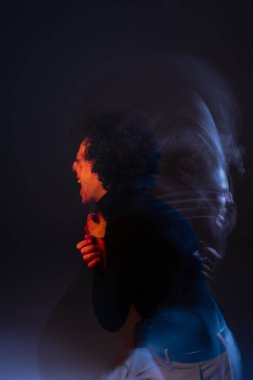 double exposure of wounded and angry african american man shouting on black background with red and blue light clipart