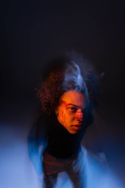 Çift taraflı Afro-Amerikan adam bipolar bozukluk ve kanayan yüz ile siyah ve mavi ışık ile kamera bakıyor