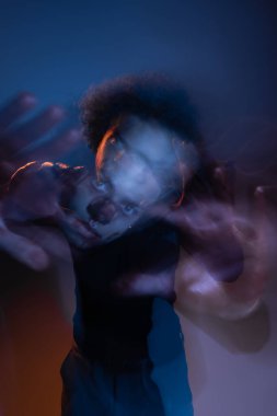 double exposure of wounded african american man with bipolar disorder looking at camera on dark with orange and blue light clipart