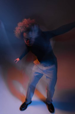 Şiddet gören ve yaralanan Afro-Amerikan erkek bipolar bozukluğunun hareket bulanıklığı turuncu ve mavi ışıkla kameraya bakıyor.