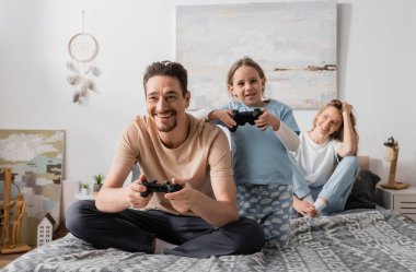 KYIV, UKRAINE - NOVEMBER 28, 2022: cheerful father and child playing video game in bedroom 