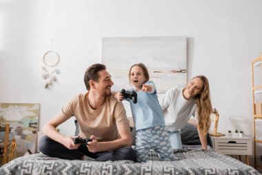 KYIV, UKRAINE - NOVEMBER 28, 2022: cheerful father looking at amazed child pointing with finger while playing video game 