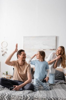 KYIV, UKRAINE - NOVEMBER 28, 2022: cheerful father and child giving high five after playing video game in bedroom 