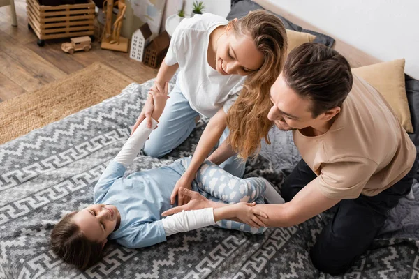 stock image high angle view of smiling parents tickling happy daughter on bed 