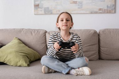 KYIV, UKRAINE - NOVEMBER 28, 2022: cheerful girl holding joystick while playing video game 