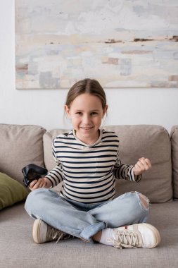 KYIV, UKRAINE - NOVEMBER 28, 2022: cheerful kid holding joystick while playing video game 