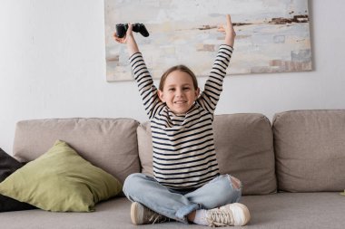 KYIV, UKRAINE - NOVEMBER 28, 2022: cheerful kid holding joystick while rejoicing after playing video game 