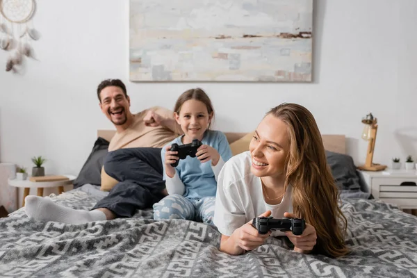 stock image KYIV, UKRAINE - NOVEMBER 28, 2022: cheerful woman and daughter playing video game in bedroom 