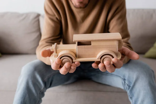 stock image cropped view of bearded man holding wooden car toy in living room 