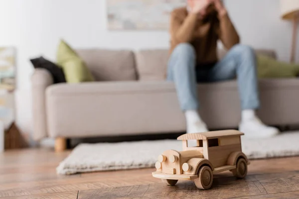 stock image wooden toy vehicle near cropped blurred man sitting on couch in living room 