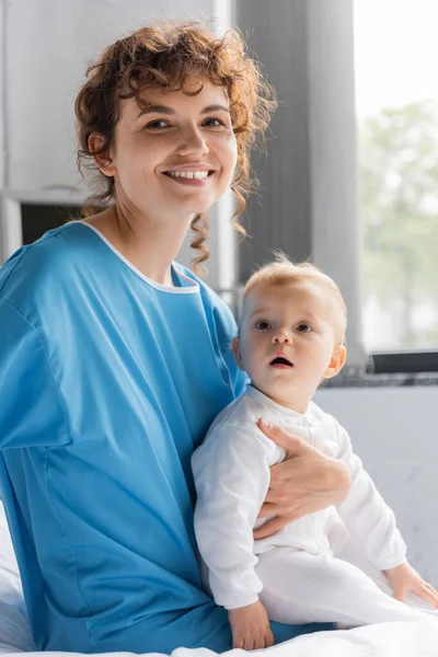 Joyful Woman Patient Gown Looking Camera While Sitting Baby Bed — Fotografia de Stock
