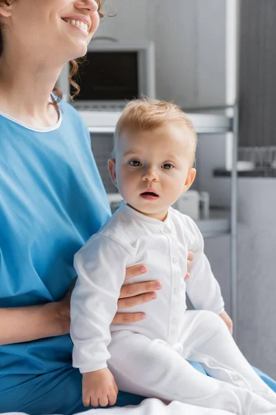 Cheerful Woman Patient Gown Holding Little Daughter Looking Camera Clinic — Fotografie, imagine de stoc