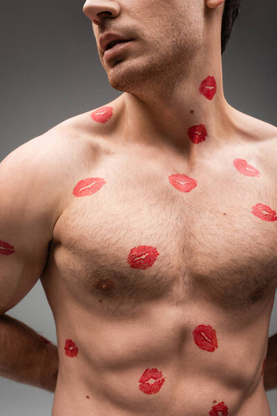 partial view of sexy shirtless man with red lipstick marks on muscular body isolated on grey