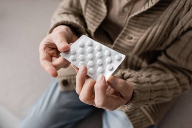 partial view of aged man with parkinsonian syndrome holding pills in trembling hands