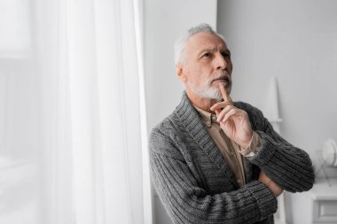 grey haired man holding hand near chin and looking away while suffering from memory loss caused by alzheimer syndrome clipart