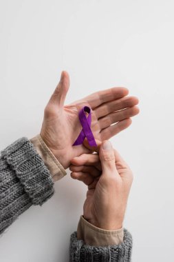 top view of cropped senior man with alzheimer disease holding purple awareness ribbon on white background