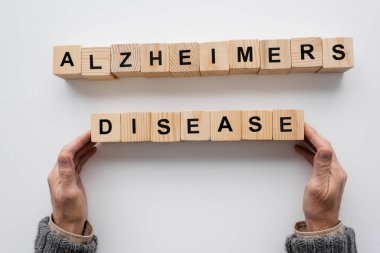 top view of cropped man touching wooden blocks with alzheimers disease inscription on white surface