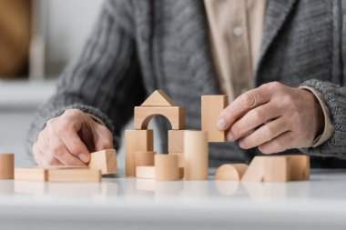 partial view of man with alzheimer syndrome playing therapy game with wooden blocks at home