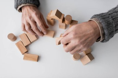 top view of cropped man with alzheimer syndrome playing with wooden blocks on white table