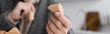 selective focus of wooden block in hand of cropped man sick on alzheimer disease on blurred background, banner