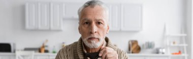 aged and depressed man with alzheimer syndrome looking at camera at home, banner clipart