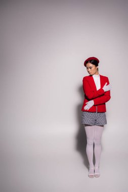 Fashionable asian woman in red and white outfit standing on grey background with shadow 