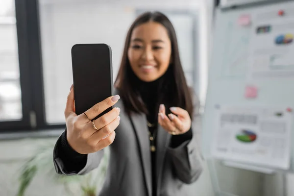 stock image Blurred asian designer looking at smartphone in studio 