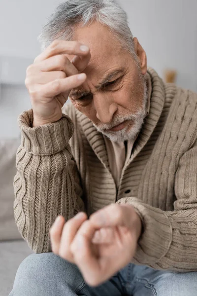 Тривожний Чоловік Паркінсоновим Синдромом Дивлячись Тремтячою Рукою Розмитому Передньому Плані — стокове фото