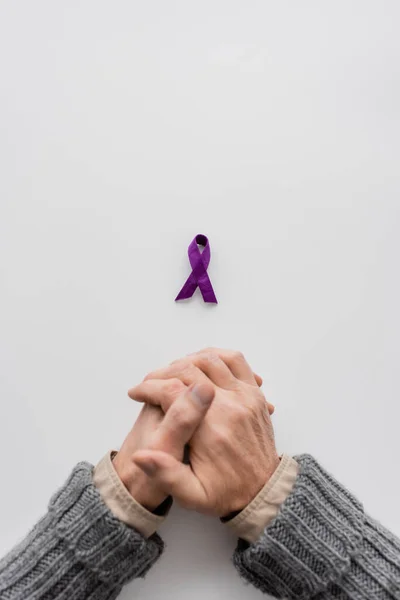 コピースペースのある白い背景に紫アルツハイマー病意識リボン付近のクロップドシニア男性のトップビュー — ストック写真