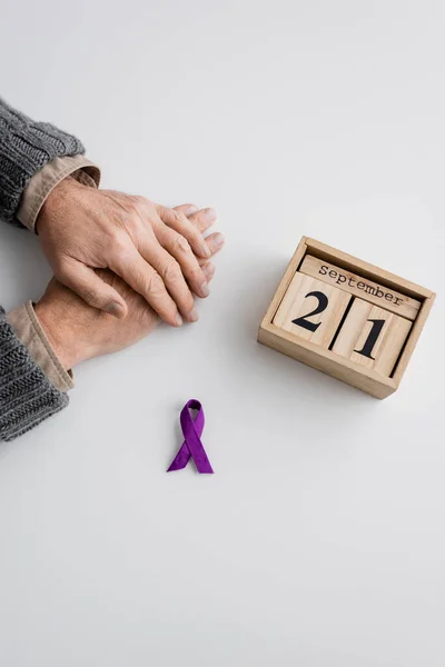 紫色のリボンと木のカレンダーのトップビュー9月21日白色の表面にアルツハイマー病とクロップドマンの近くの日付 — ストック写真