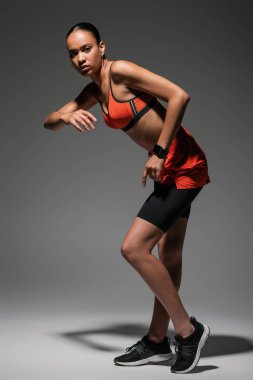 full length of young african american sportswoman in sportive shoes working out on grey 