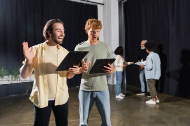 redhead and brunette students holding scenarios and rehearsing in acting skills school