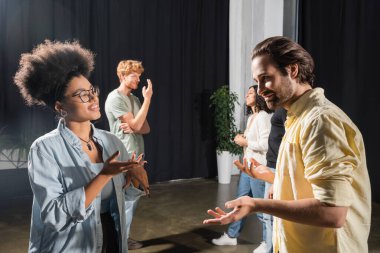 smiling multiethnic actors gesturing during conversation in acting skills school clipart