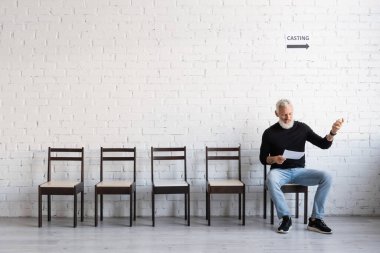 bearded middle aged actor reading screenplay while waiting for casting in hall