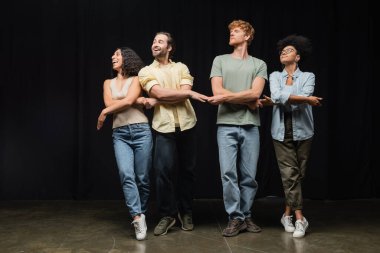 young and smiling multiethnic actors rehearsing small swans dance on stage in theater school