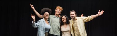 troupe of smiling multicultural actors hugging and waving hands in theater, banner