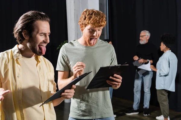 Brunette Redhead Men Sticking Out Tongues While Reading Scenarios Rehearsal — Zdjęcie stockowe