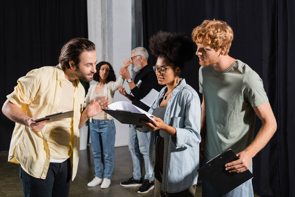 young multicultural actors looking at screenplay during rehearsal in acting skills studio