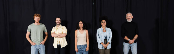 bearded art director with young interracial actors smiling at camera in theater school, banner
