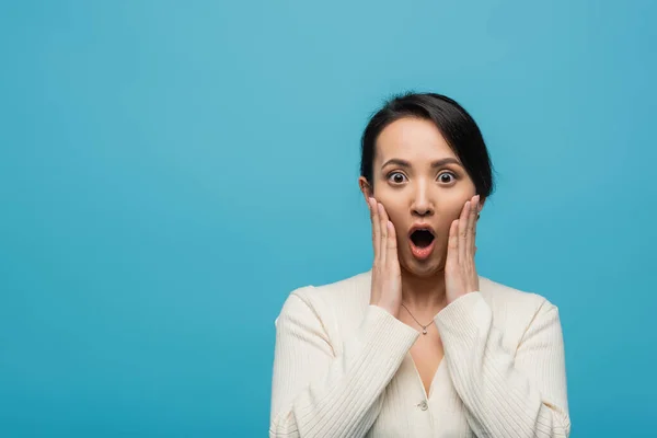 stock image Shocked asian woman touching cheeks isolated on blue 