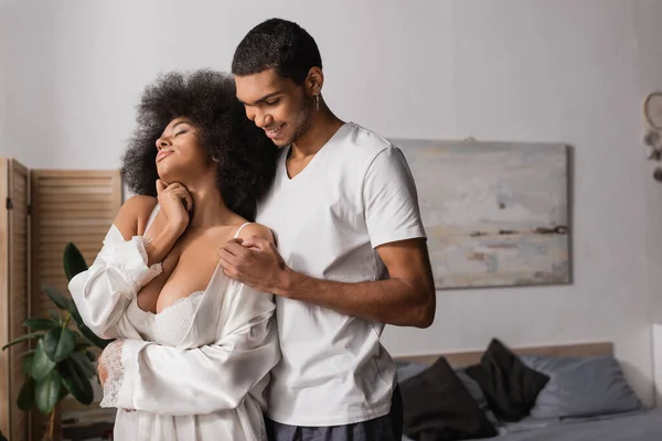 Smiling African American Man Hugging Sexy Girlfriend White Robe Lingerie — Stockfoto