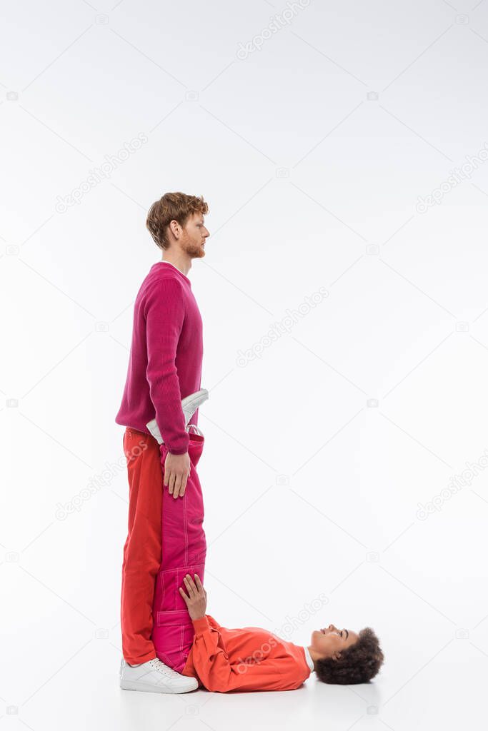 Side view of interracial couple in magenta color clothes showing L letter on white background