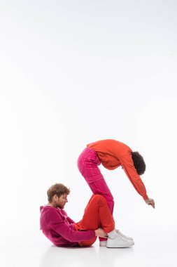 side view of interracial couple in magenta color clothes showing s letter on white background  clipart