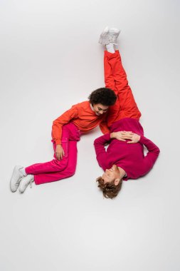 Kırmızı elbiseli mutlu Afro-Amerikan kadını beyaz giyinmiş neşeli bir adama bakıyor. 