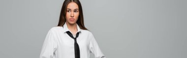 brunette woman in white shirt and tie looking away isolated on grey, banner  clipart