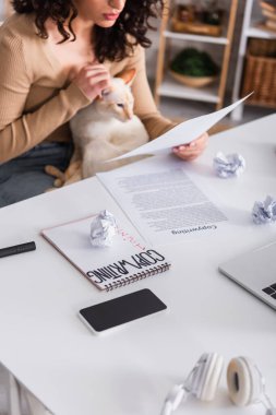 Cropped view of devices and papers near copywriter holding oriental cat at home  clipart