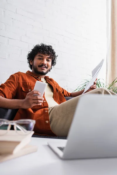 Indian Freelancer Holding Papers Using Gadgets Couch Home — Stockfoto
